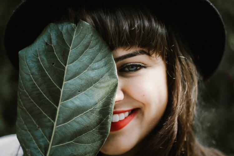 Girl Smiling Behind Leaf